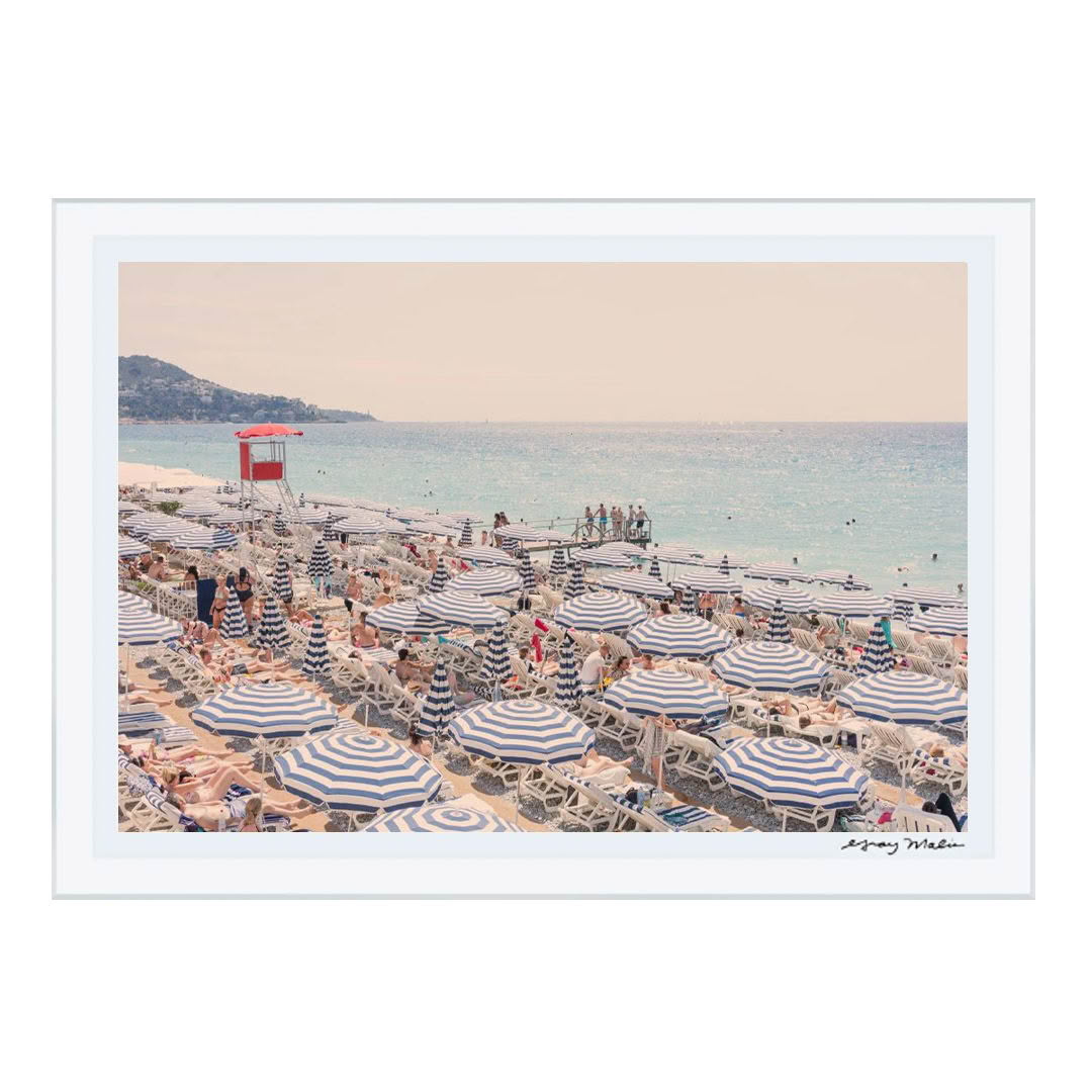 Crowded beach with striped umbrellas and hillside view