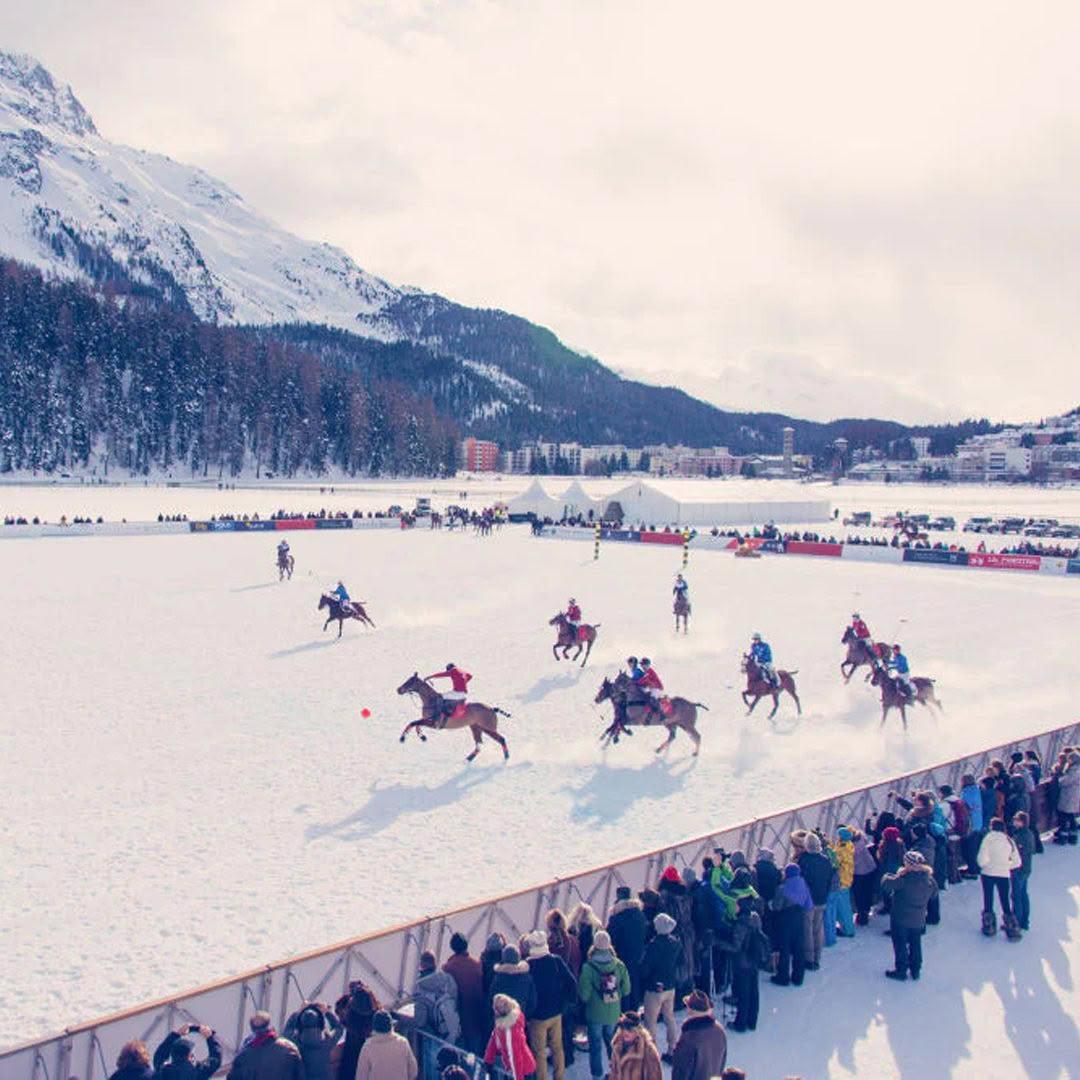 Snow polo match in mountainous landscape with spectators