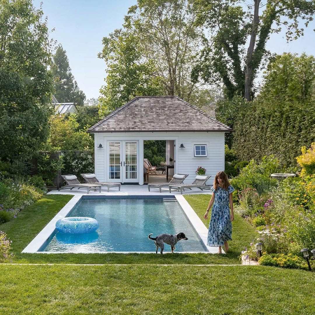 Woman walking dog by serene backyard pool and garden