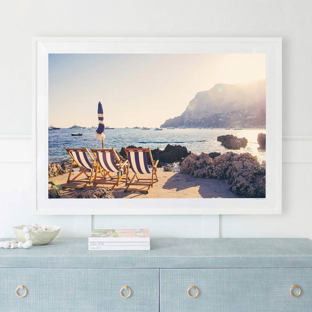 Beach scene with chairs, person, and distant boats