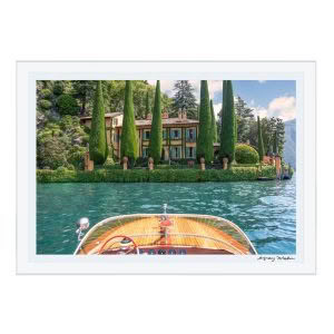 Vintage boat approaching lush lakeside villa