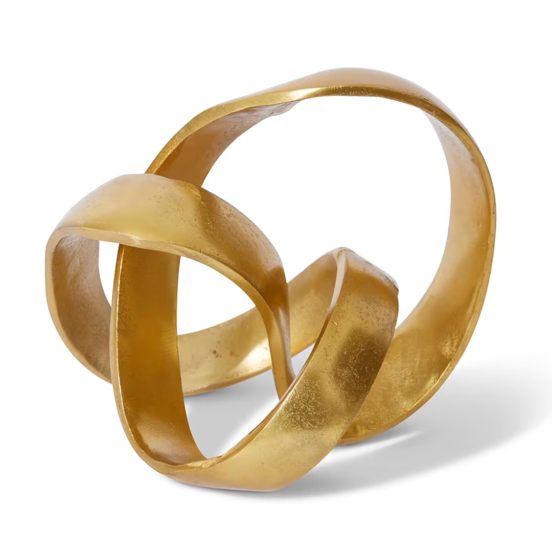 Golden intertwined sculptural metal bands on white.