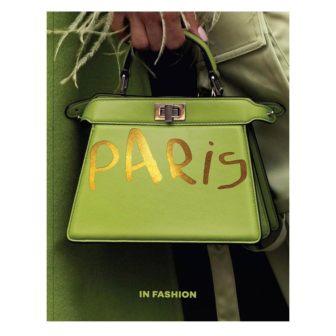 Green handbag with golden 'PARIS' text held by person