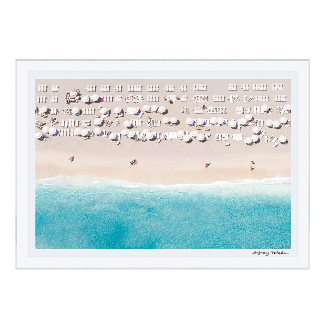 Aerial view of crowded beach with umbrellas and surf.