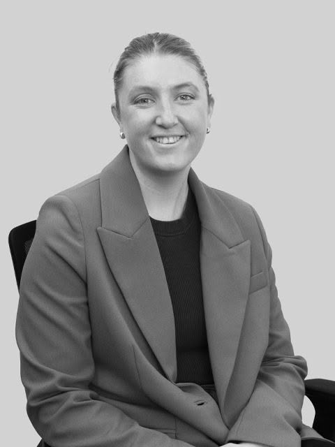 Smiling woman in brown blazer seated in office chair