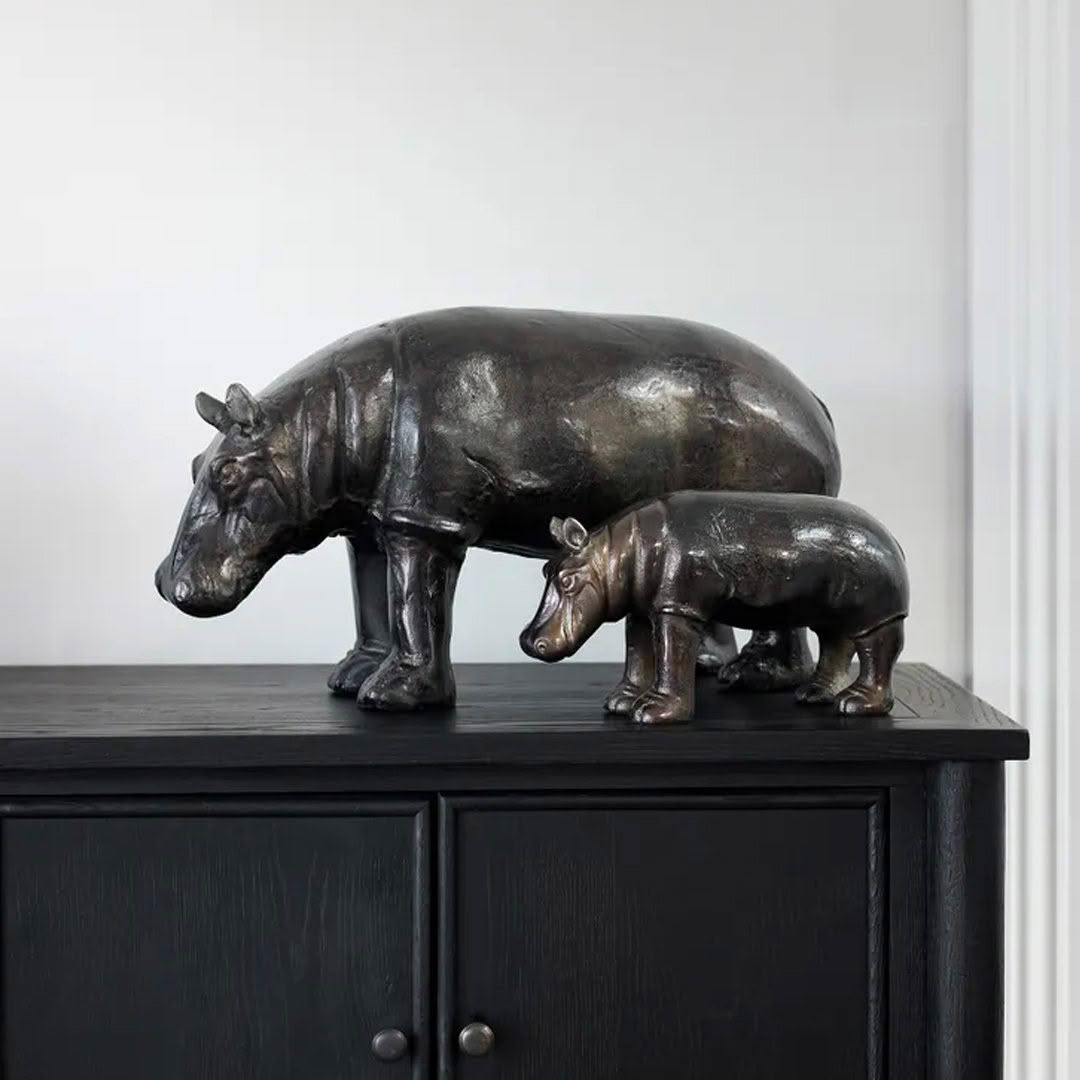 Bronze hippopotamus sculptures on dark cabinet