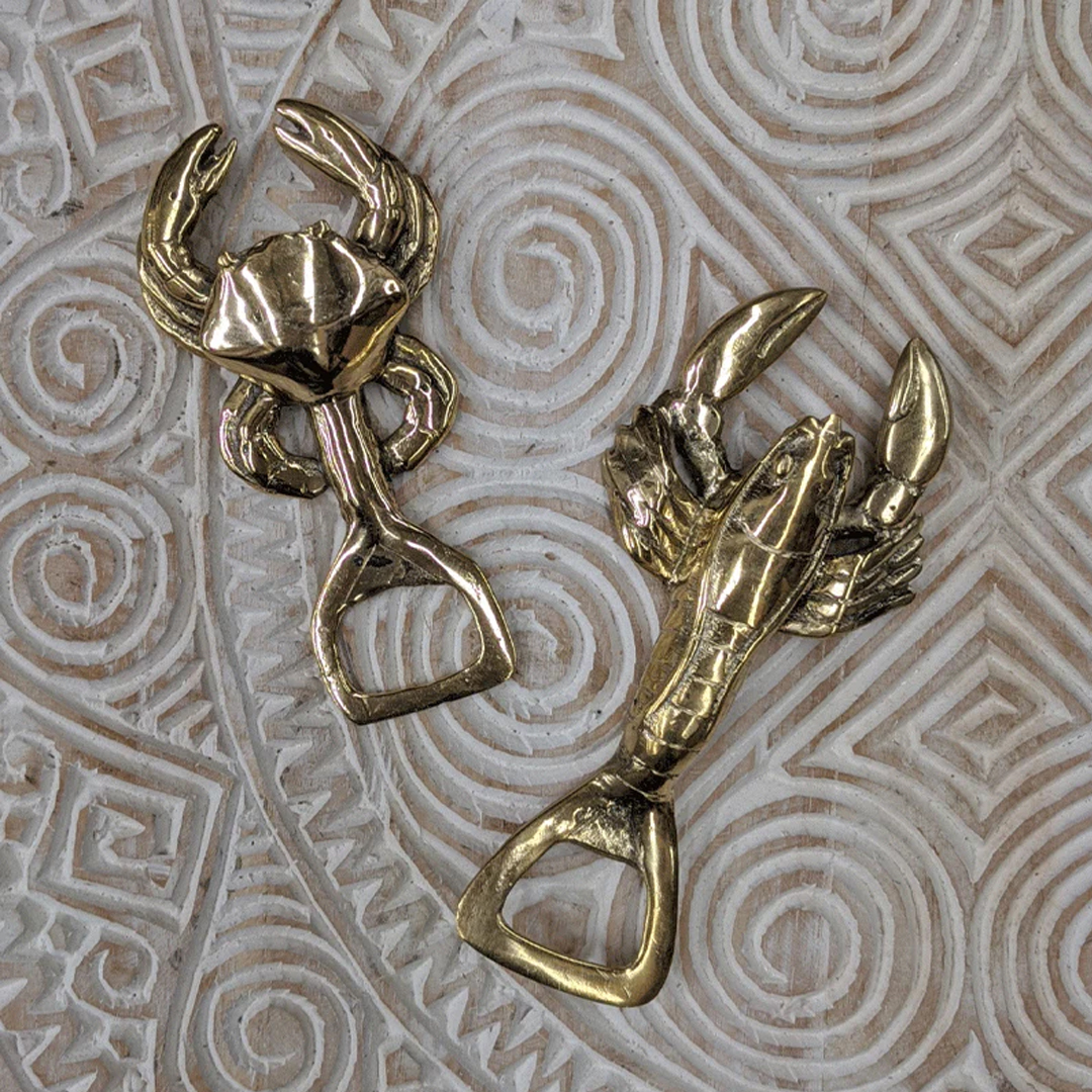 Bronze lobster and crab bottle openers on patterned background