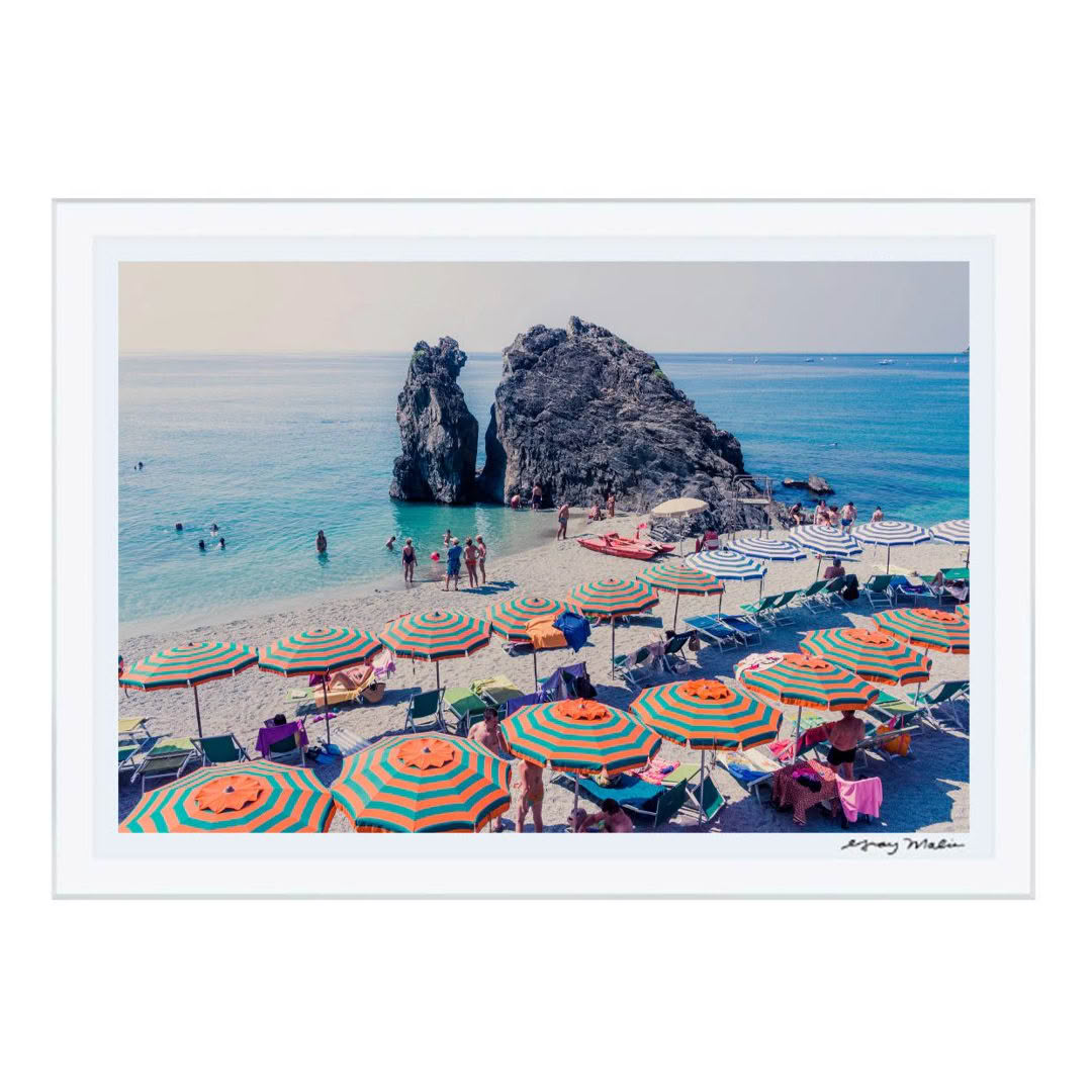 Colorful beach umbrellas by sea with rocky outcrop