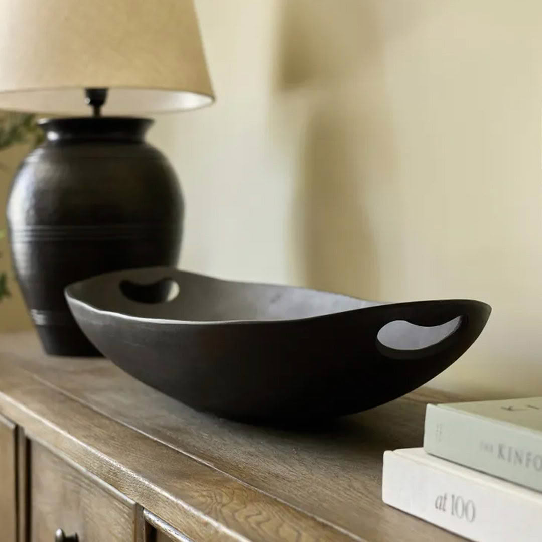 Dark bowl on table with lamp and books