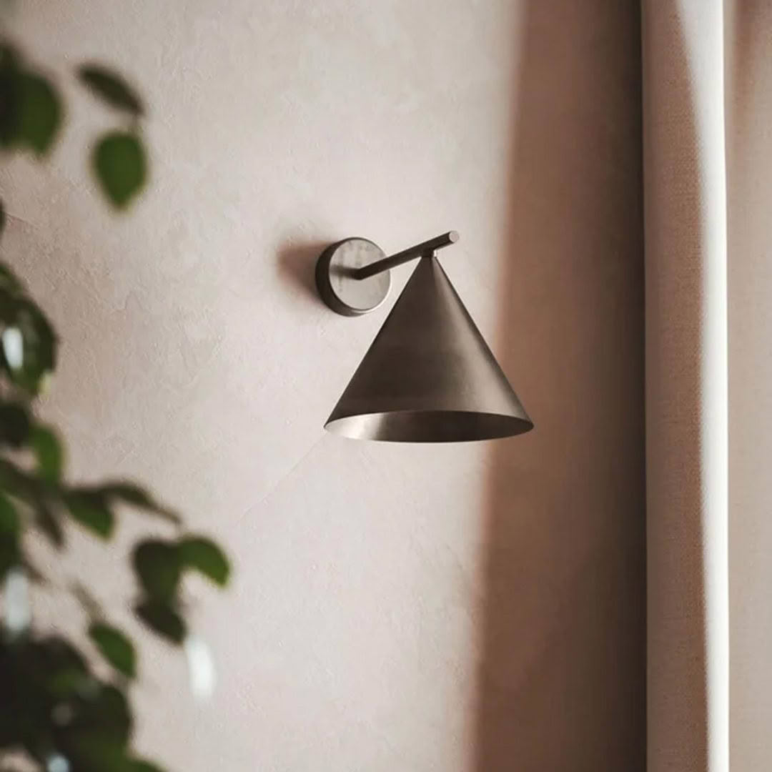 Minimalist wall-mounted cone lamp beside curtain