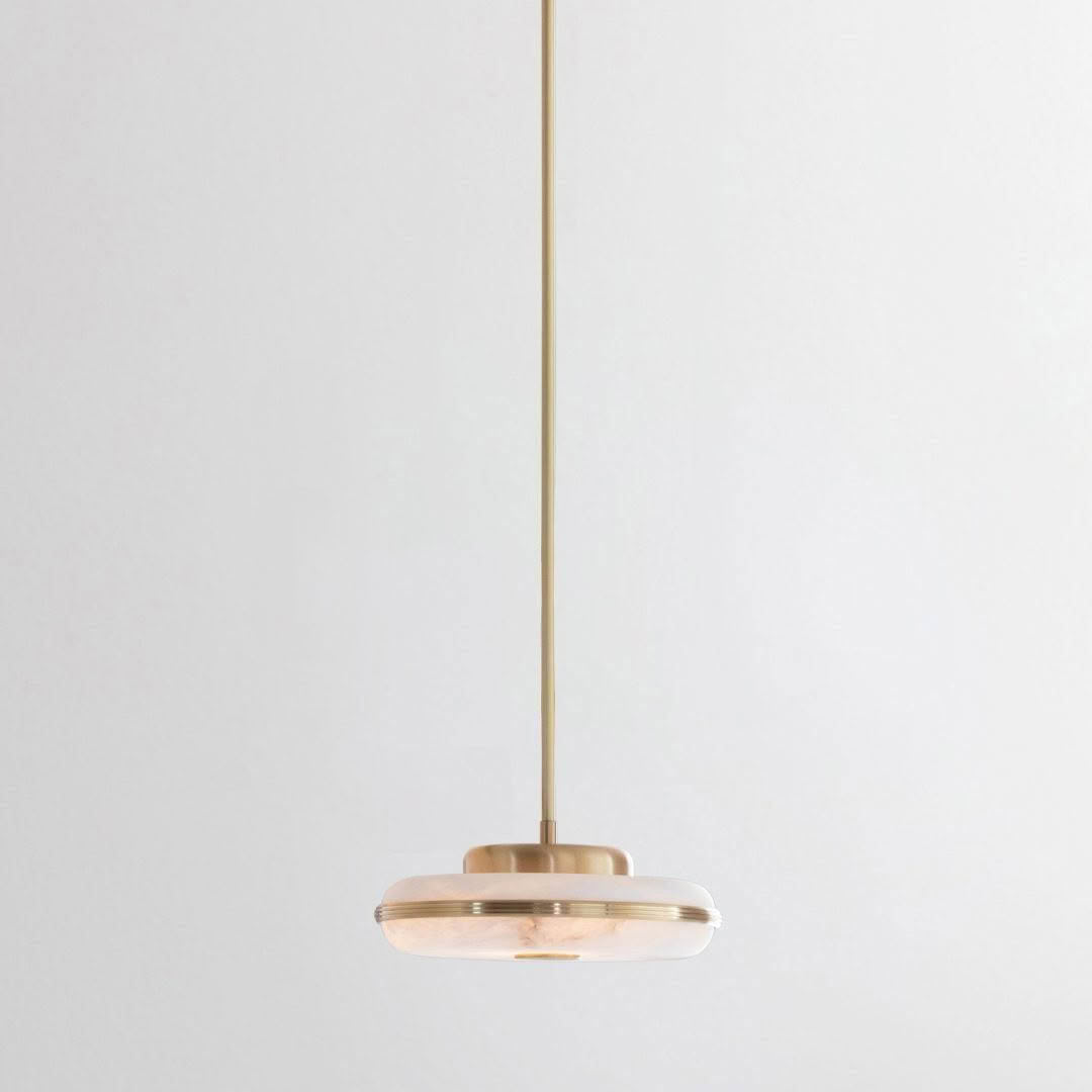 Minimalist gold pendant light against white background
