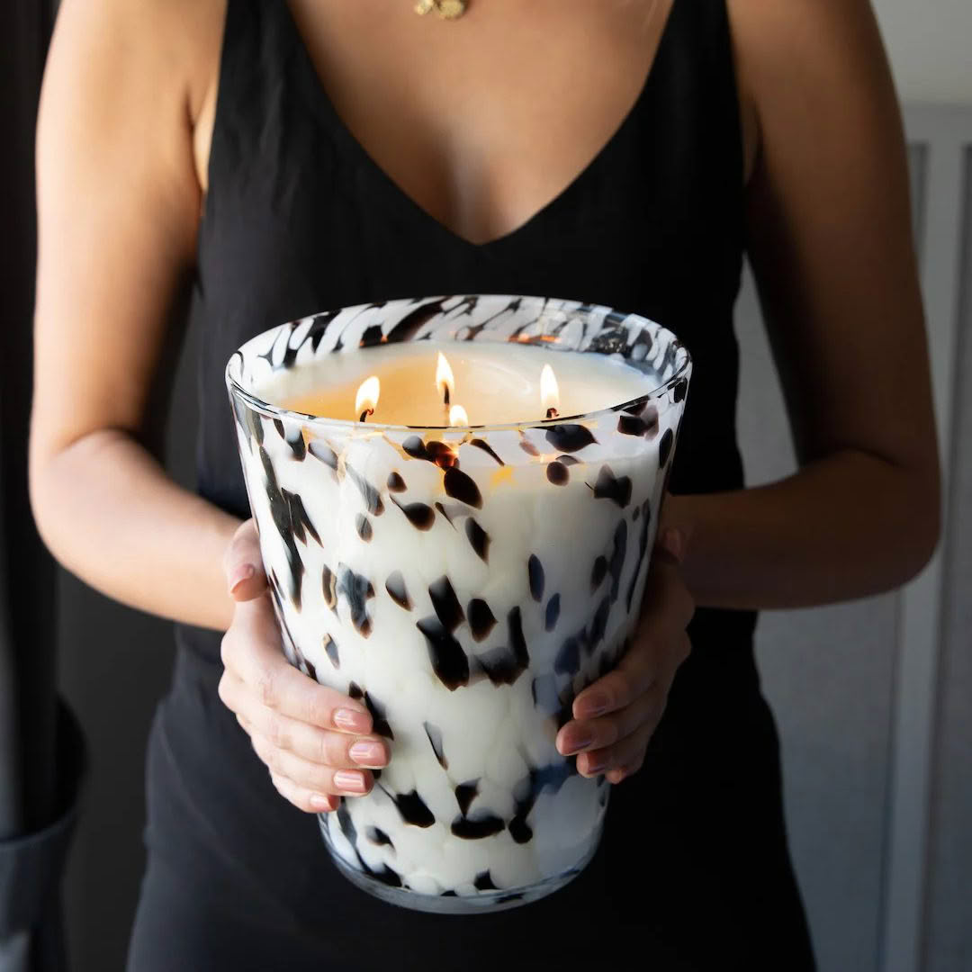 Woman holding large spotted lit candle