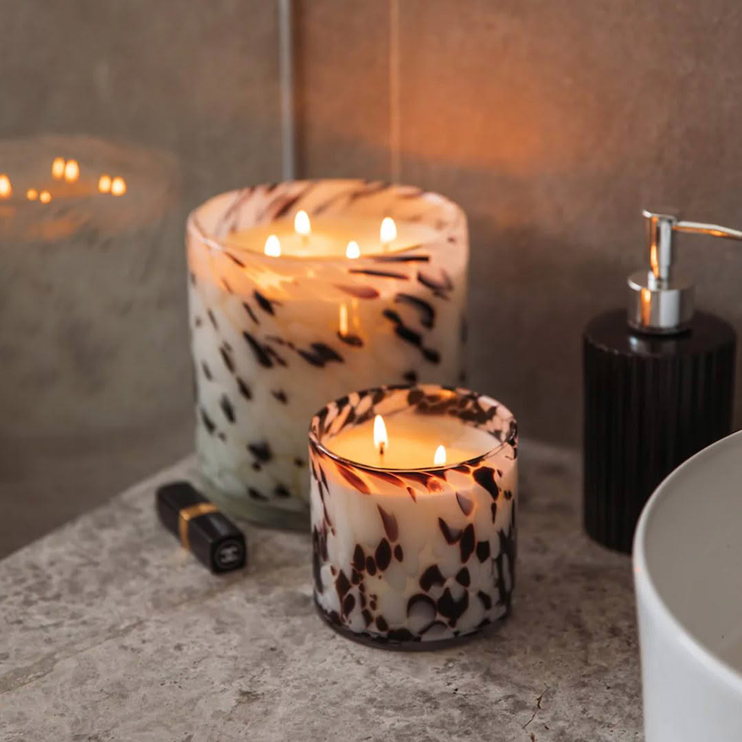 Illuminated spotted candles on bathroom countertop