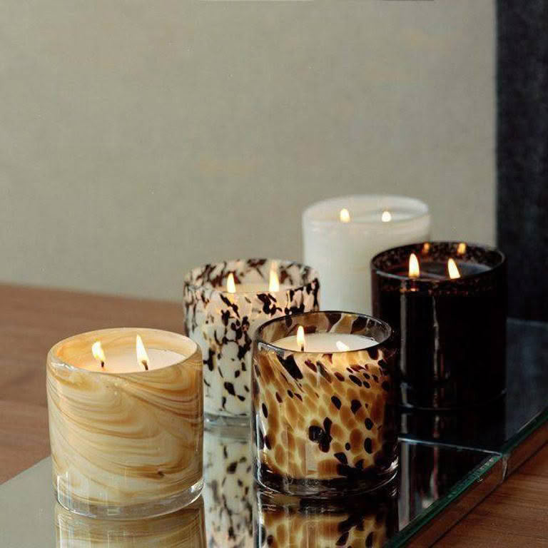 Various patterned candles lit on reflective surface
