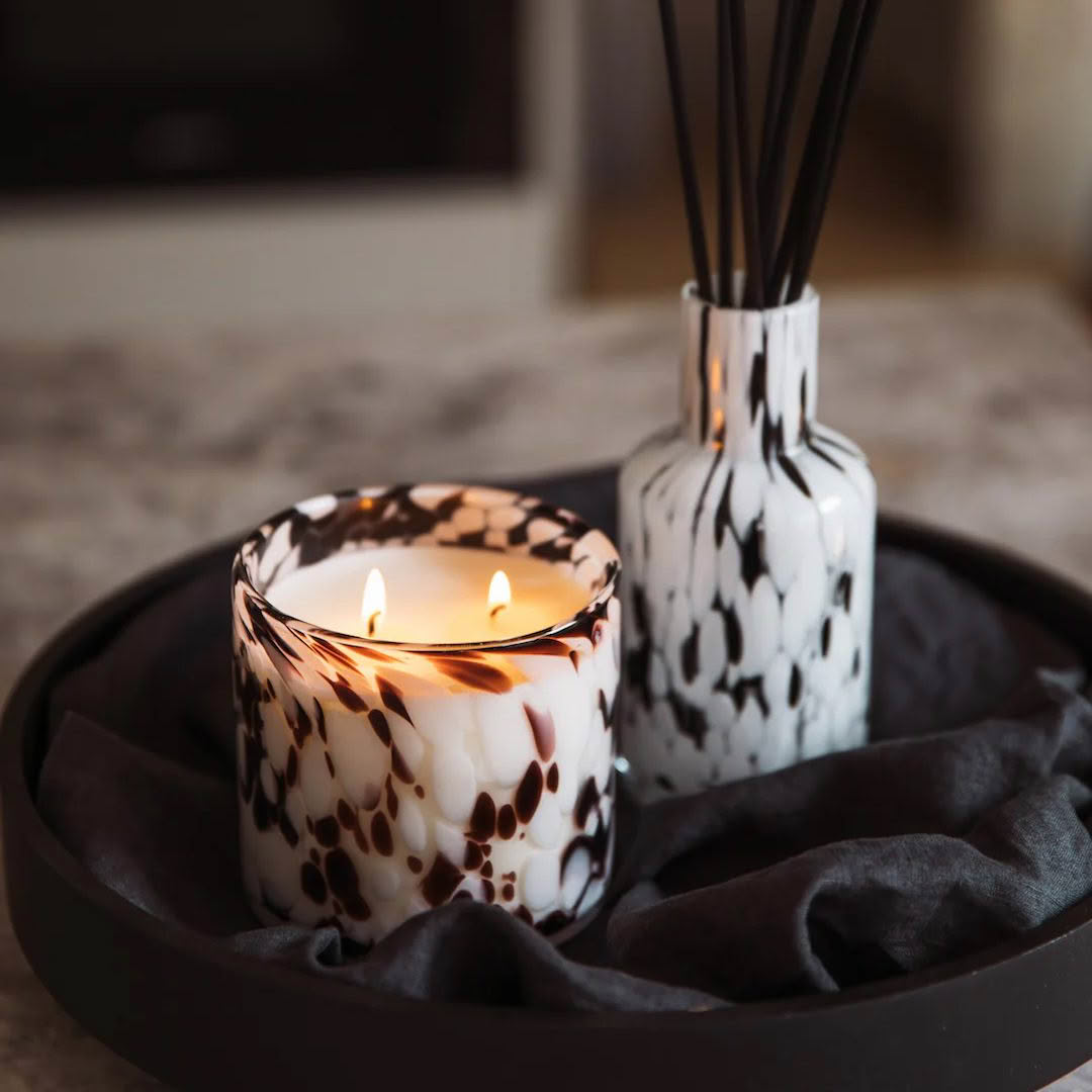 Lit candle and diffuser on tray, elegant home decor