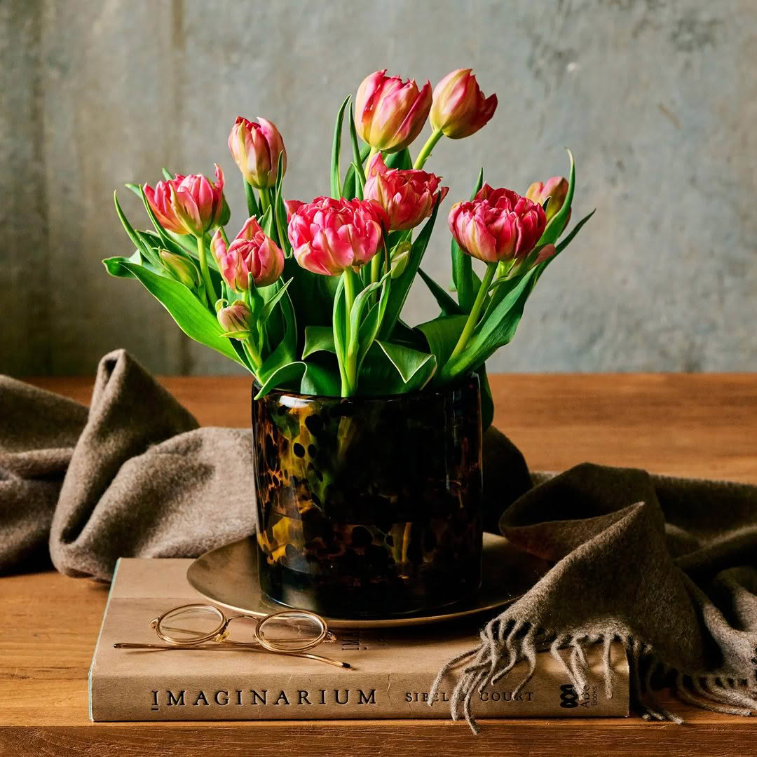 Pink tulips in decorative vase on wooden table