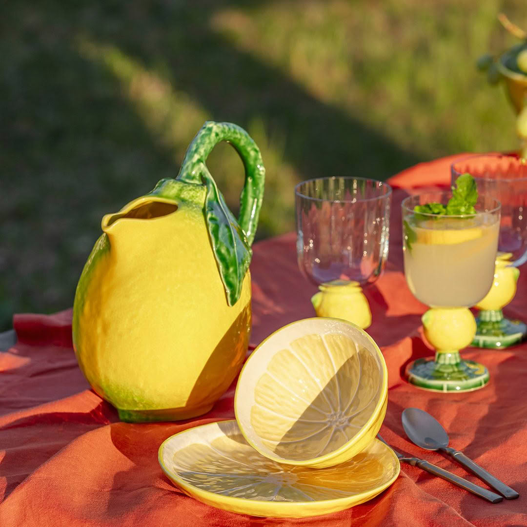 Lemon-themed picnic setup with pitcher and glasses outdoors