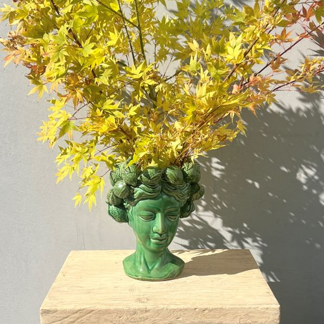 Green bust planter with yellow autumn leaves