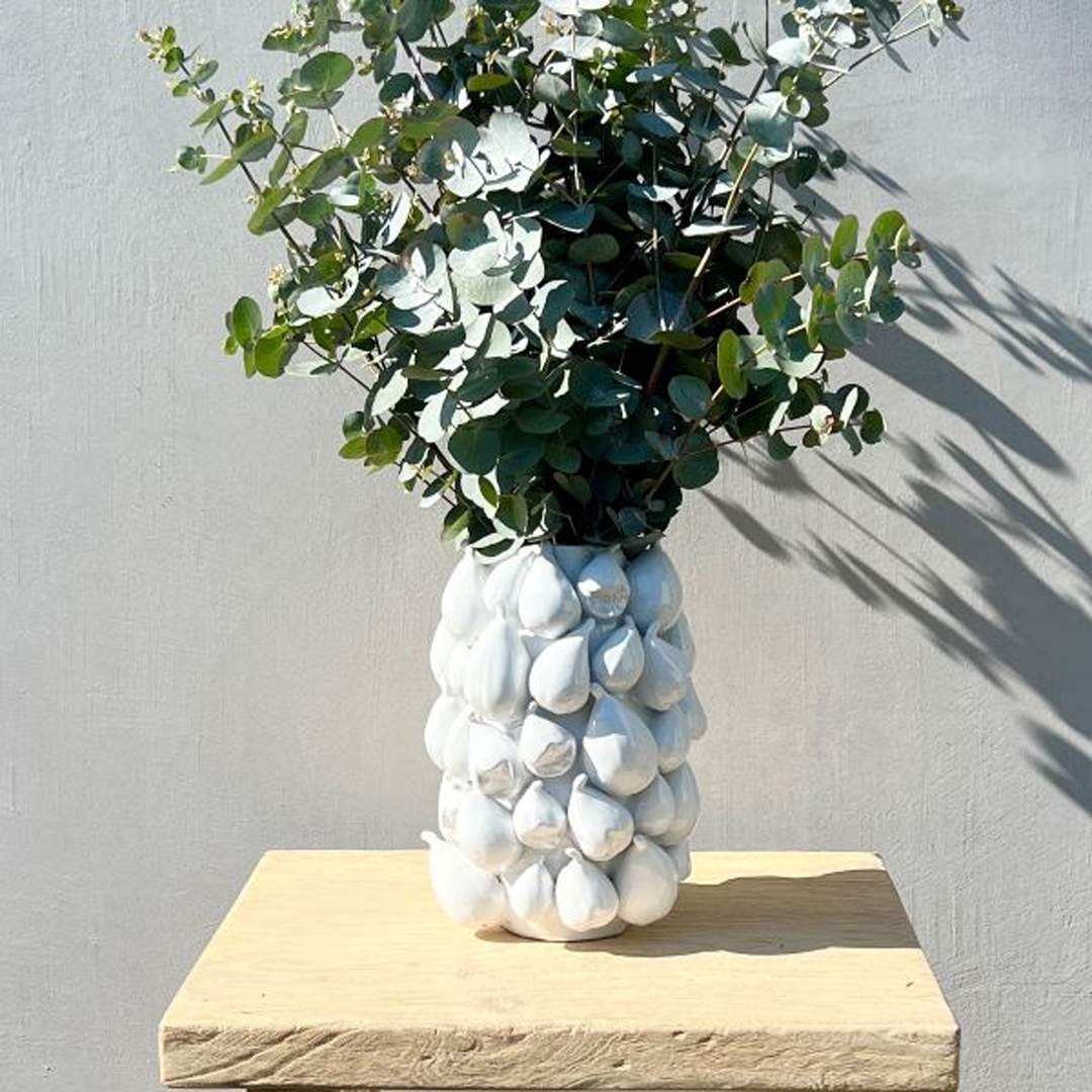 Eucalyptus in decorative white pineapple vase on wooden stand