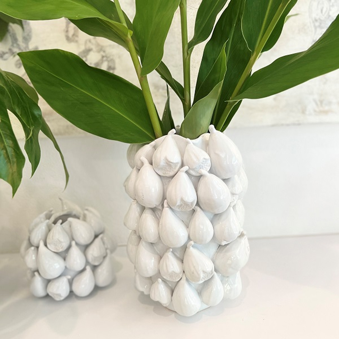 White ceramic vase with bulbous design holding green leaves