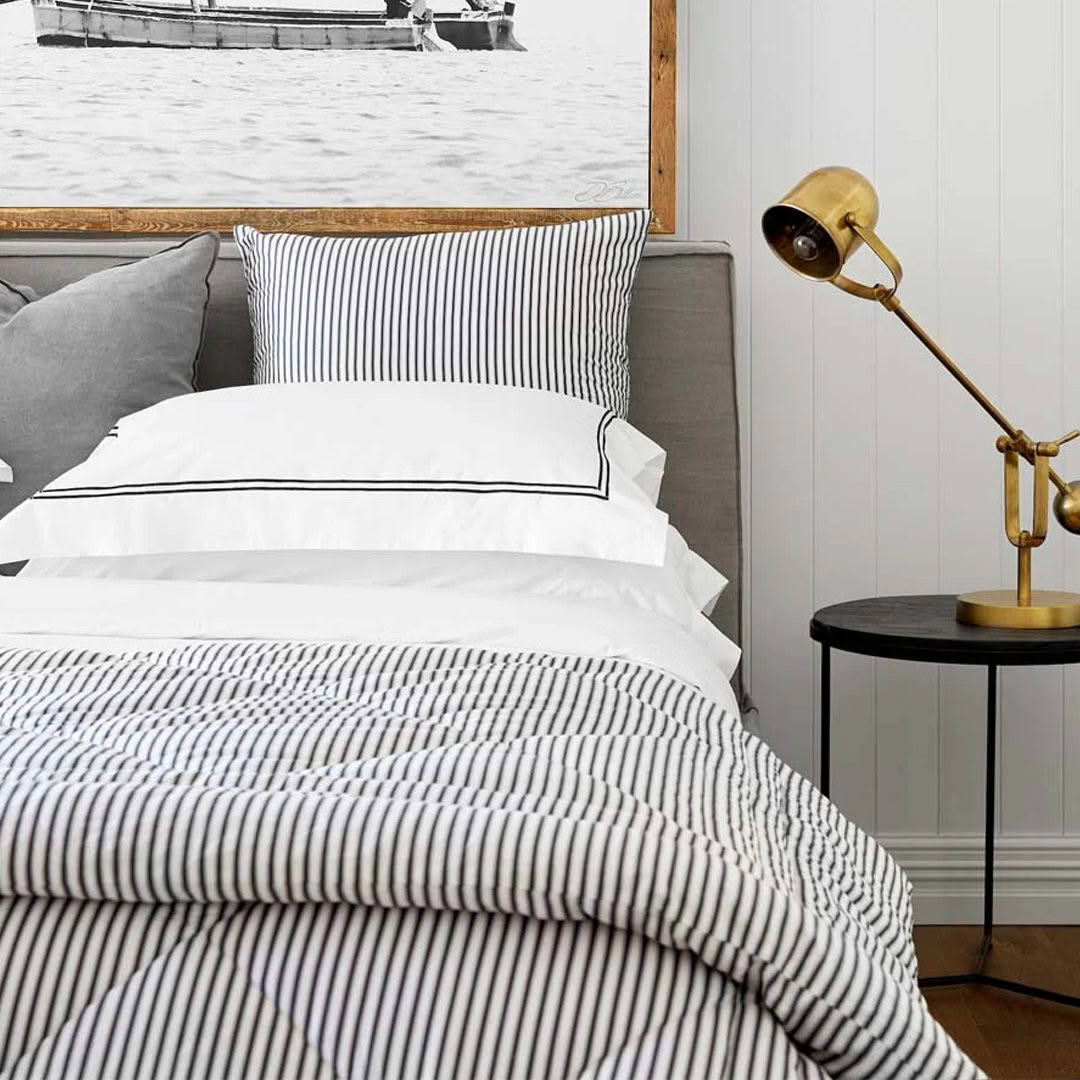 Cozy bedroom with striped bedding and brass desk lamp.