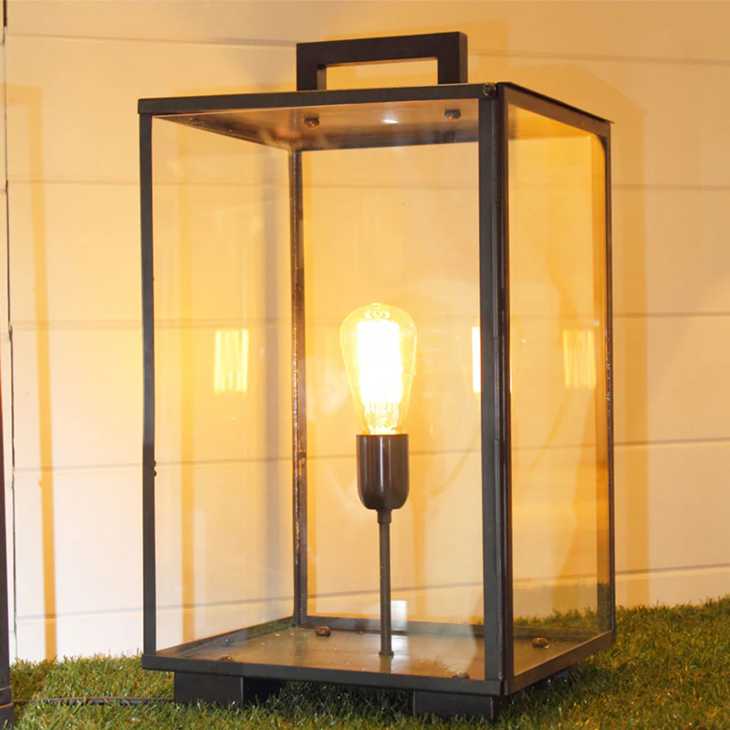 Illuminated outdoor lantern on grass at night